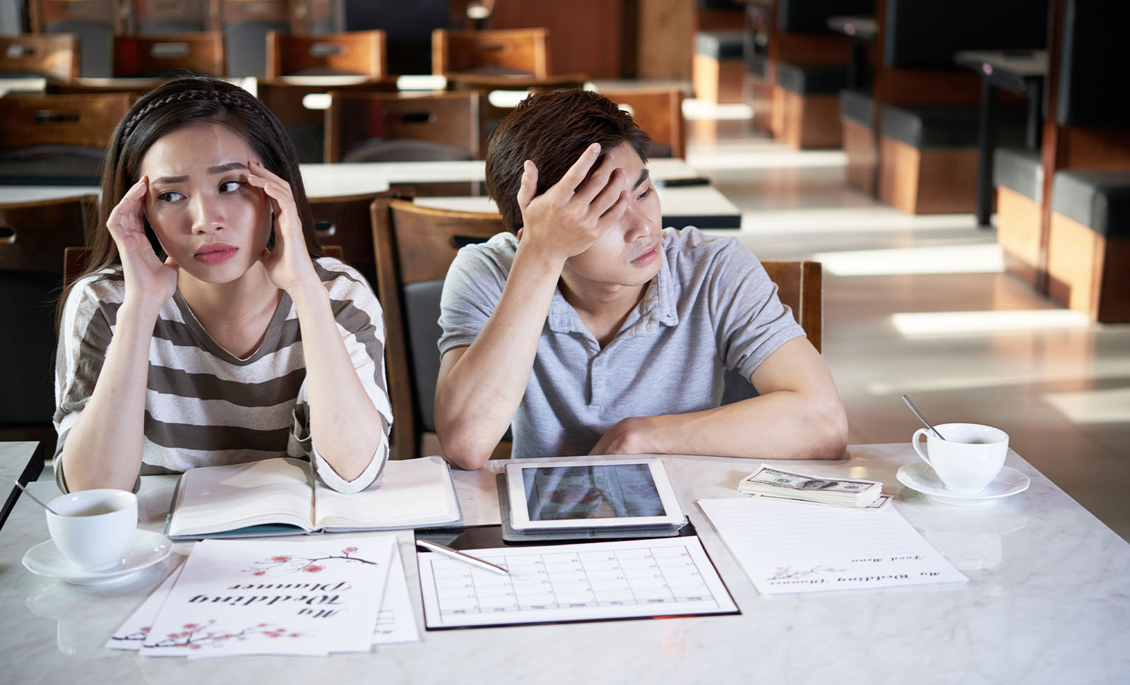stressed couple looking at laptop wedding planning papers